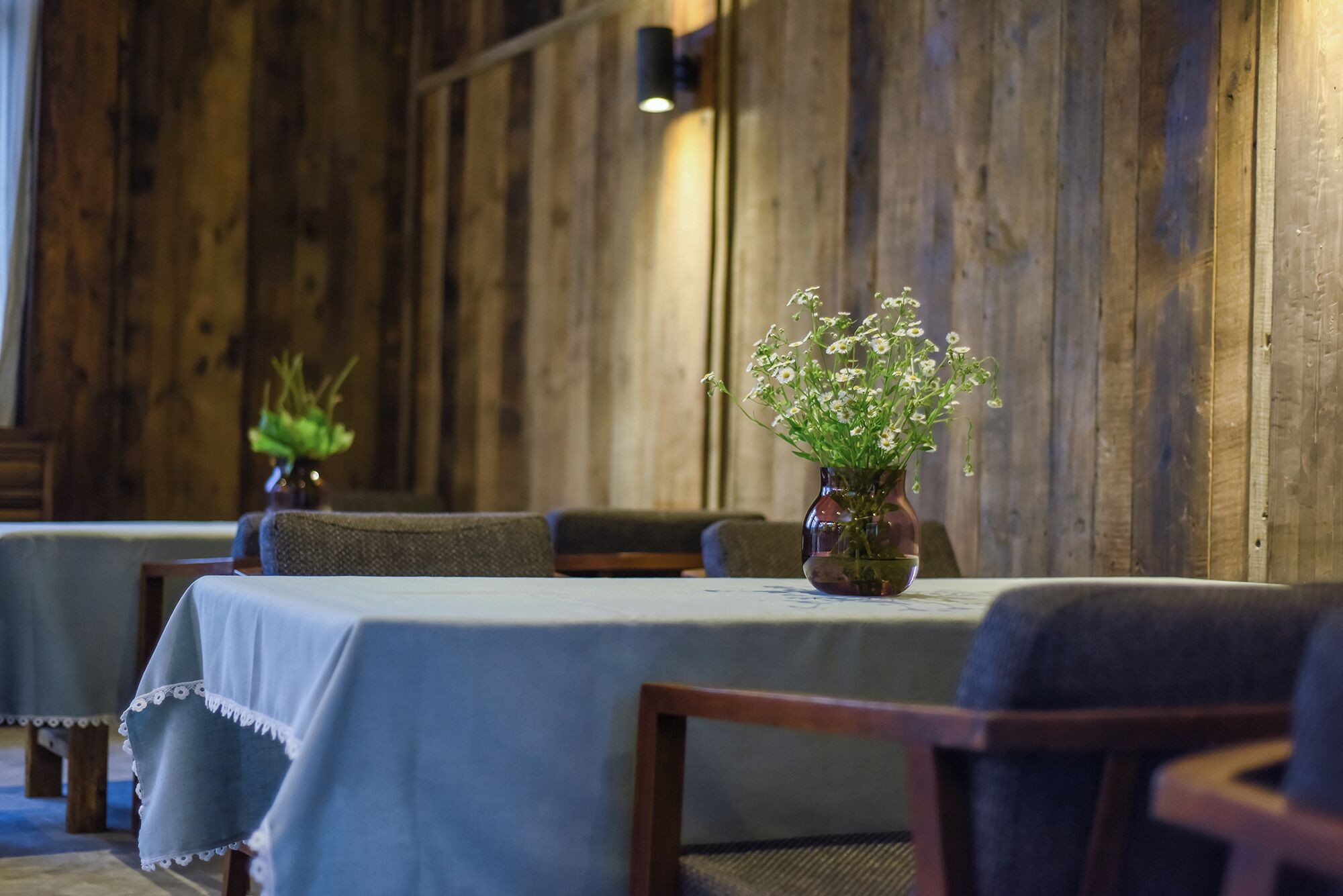 Un espace repas avec des murs en bois, des tables recouvertes de nappes bleues et des chaises.
