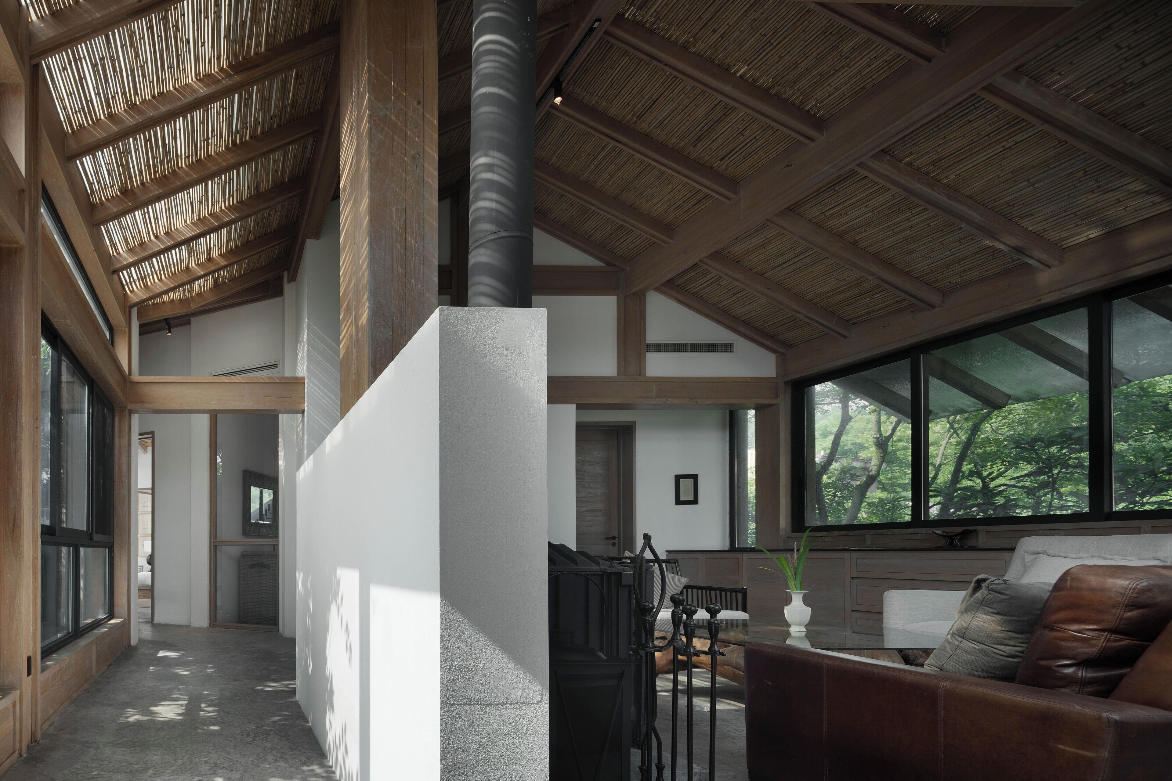 Spazioso interno con soffitto alto, ampie finestre e una zona salotto centrale con divano e poltrone.