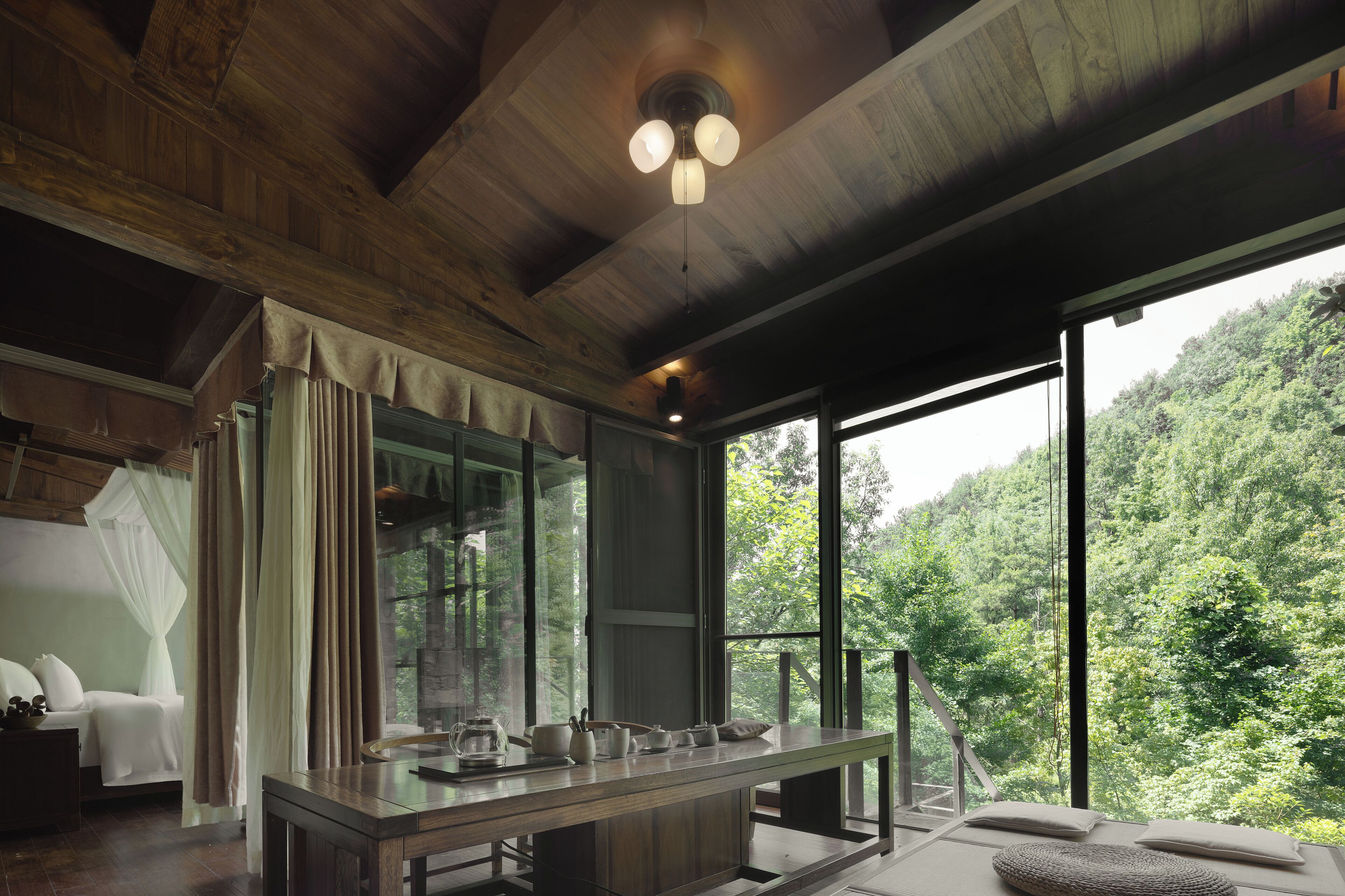 A room with a large window, a wooden ceiling, and a bed with white bedding.