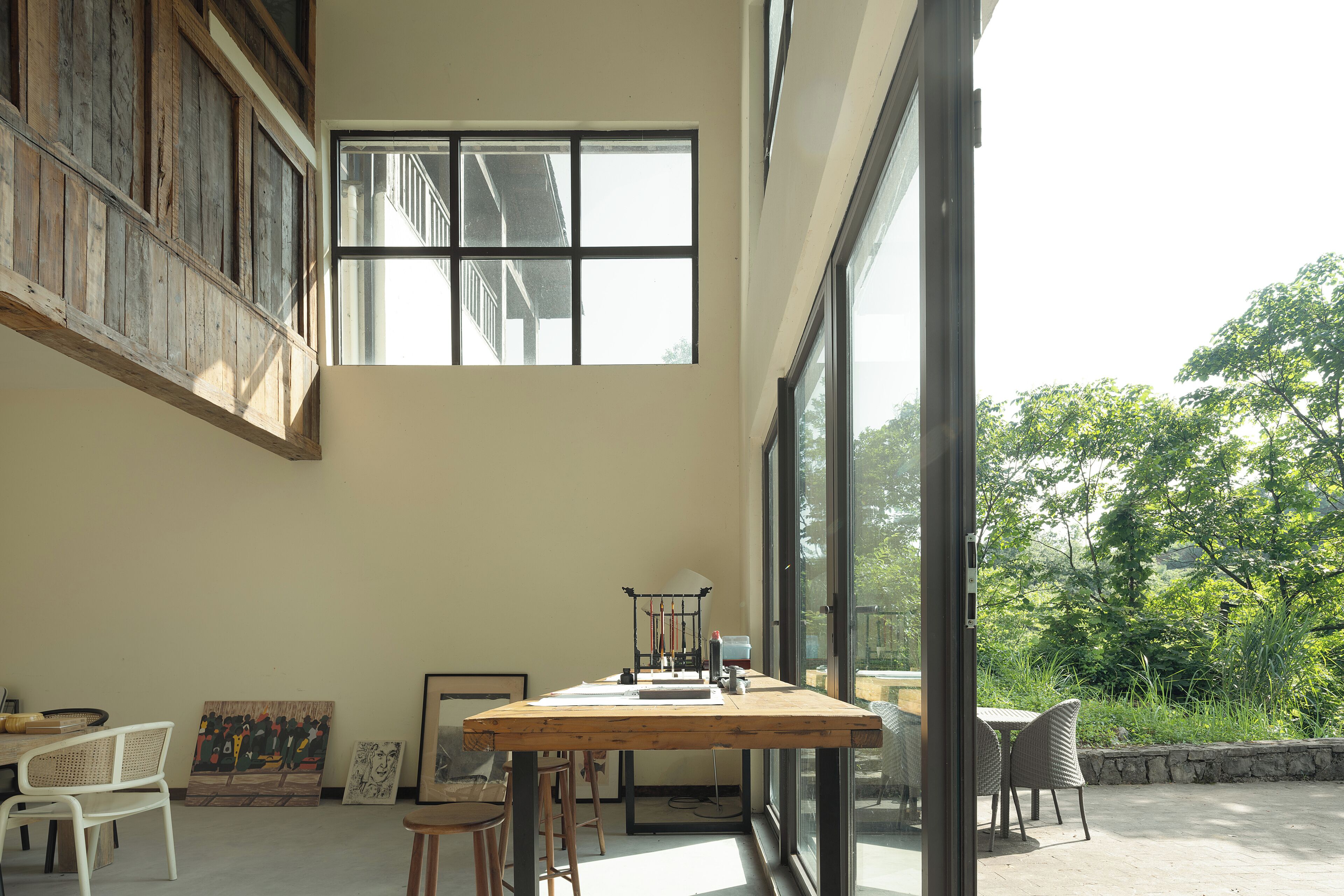 Une pièce spacieuse avec une grande table en bois, une chaise blanche et un tableau accroché au mur.