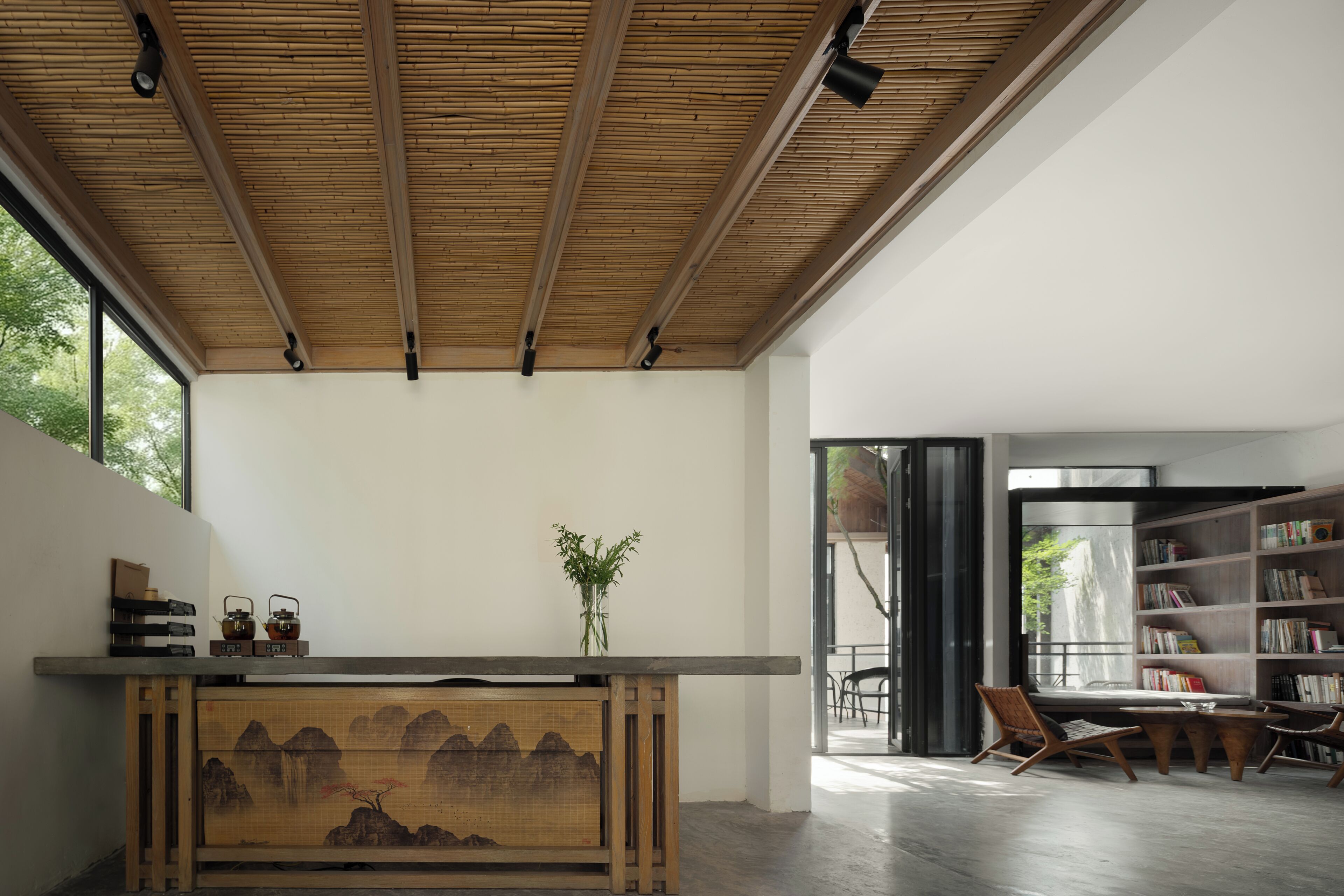 A modern interior with a wooden ceiling, a bookshelf, and a painting on the wall.