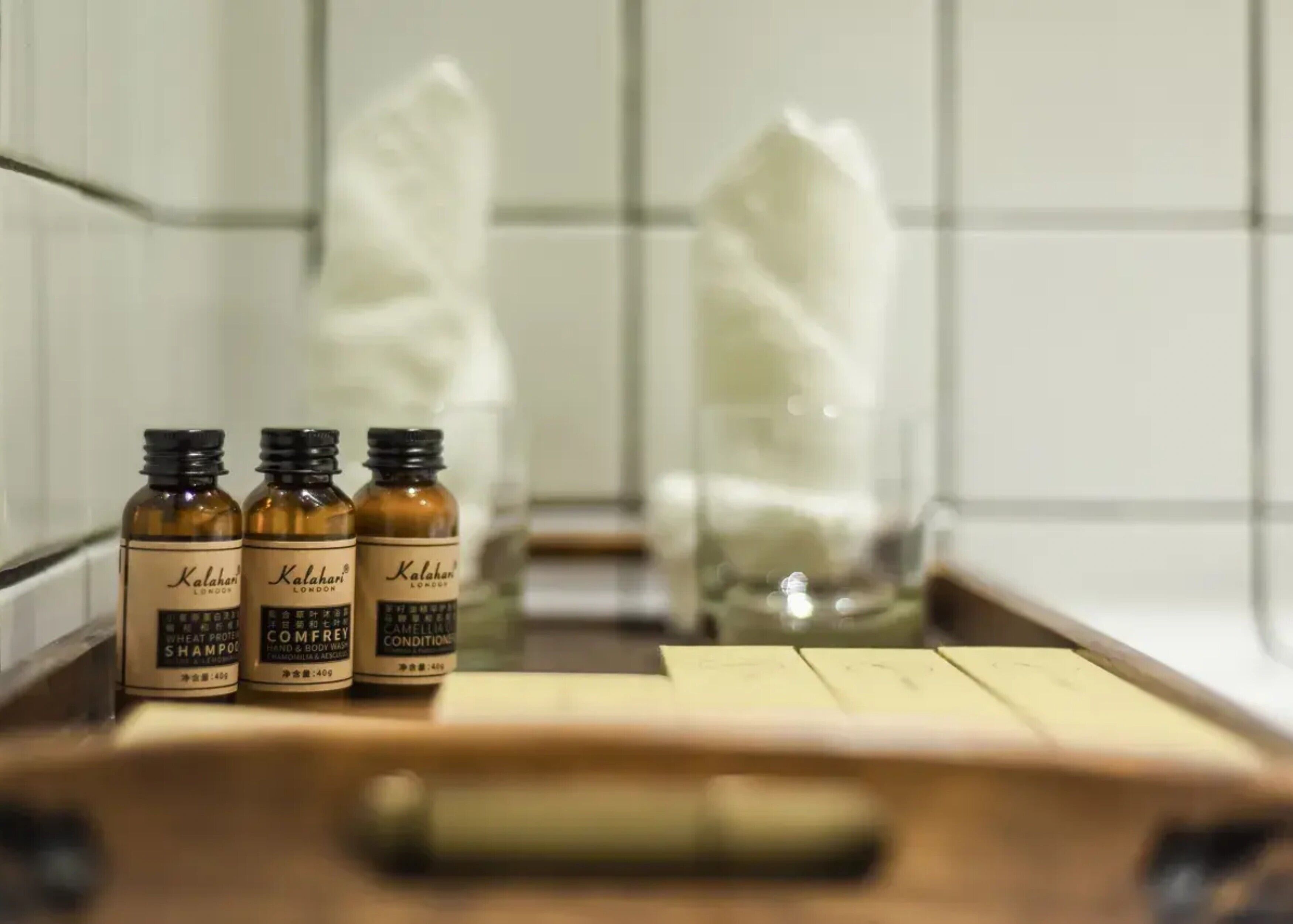 Three bottles of shampoo and conditioner on a counter with a tissue box and a tissue roll.