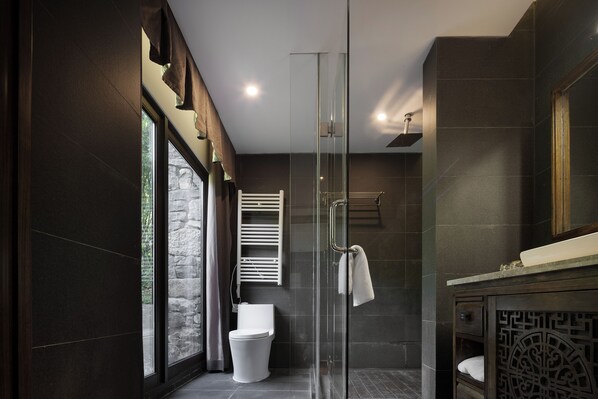 Un baño moderno con ducha envuelta en vidrio, inodoro blanco y tocador con gabinete decorativo.