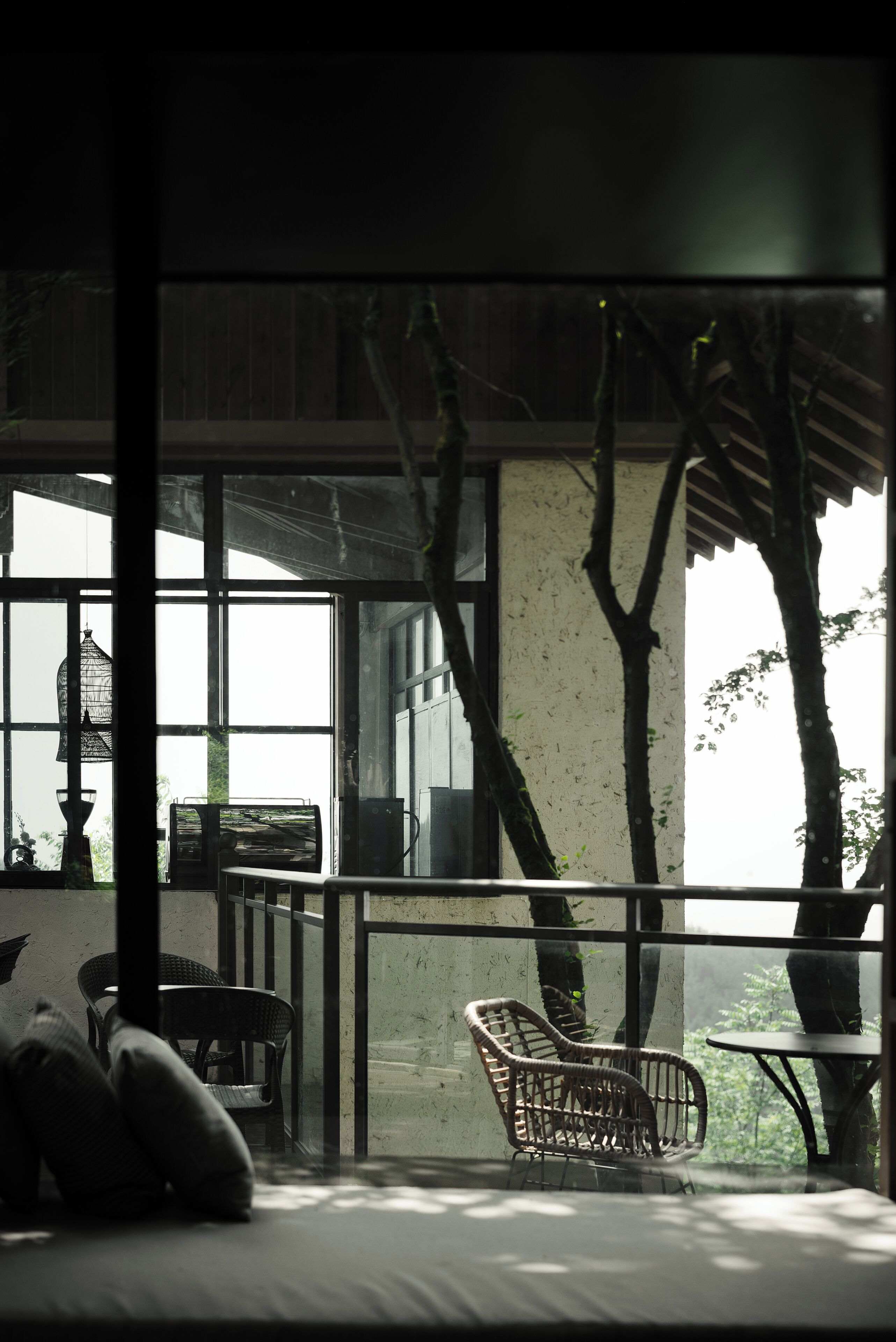 A room with a large window, wicker furniture, and a view of trees outside.