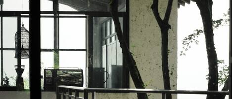 A room with a large window, wicker furniture, and a view of trees outside.