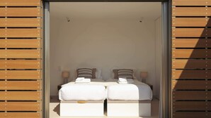 Una stanza con due letti, ognuno con biancheria da letto bianca e cuscini decorativi.