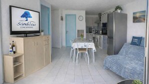 A compact living space with a dining area, kitchenette, and a sofa.