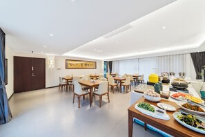 A spacious dining area with multiple tables and chairs, a buffet setup with various food items, and a large painting on the wall. - Kunming Boyue Hotel (Kunming)
