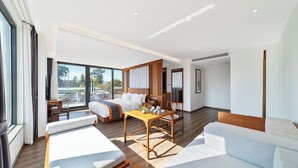 A modern hotel room with a large bed, a sofa, a dining table, and a balcony with a view.