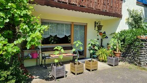 Una casa con balcón, una banca y plantas en macetas.