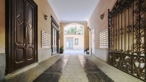 A corridor with a tiled floor, large wooden doors, and a wrought iron gate. - Urban Design Studio | Buenos Aires District (Milano)