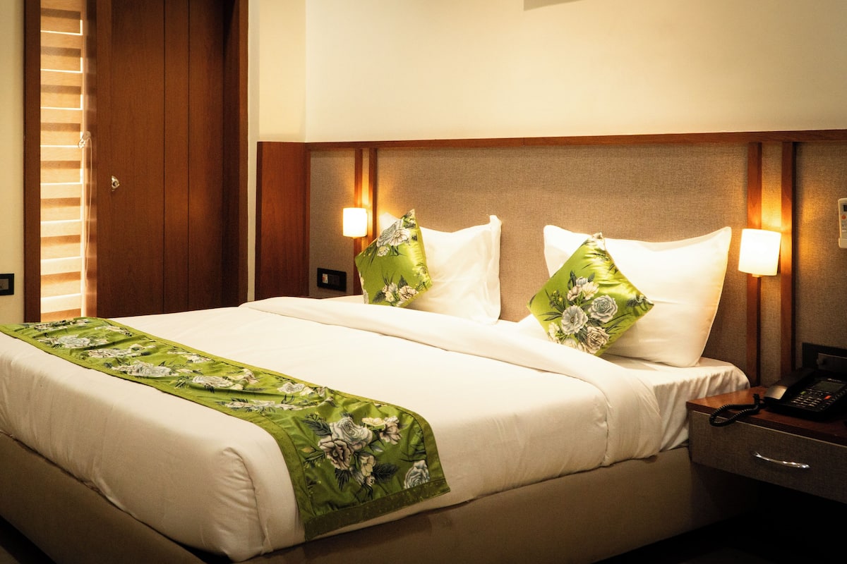 A hotel room with a large bed, two bedside lamps, a telephone, and a nightstand.