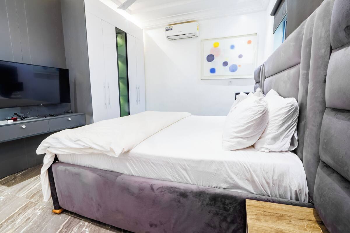 A modern bedroom with a bed, TV, and wardrobe.
