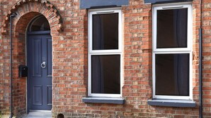 A brick building with a dark blue door and two windows with white frames. - Ocho Homes By Eight Continents - R7 (Belfast)