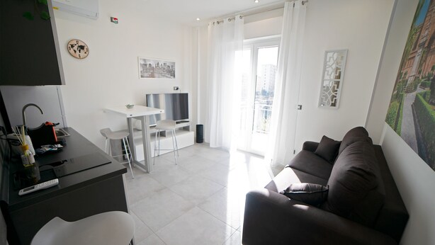 A modern living room with a sofa, a dining area with a table and chairs, a TV, and a large window with curtains. - City Life Palermo (Palermo)
