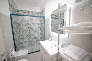 Ein modernes Badezimmer mit Duschkabine aus Glas, einem weißen Waschbecken und einem Spiegel.
