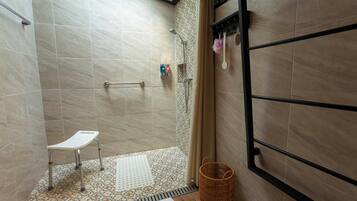 A shower area with a white chair, a patterned floor, and a basket.