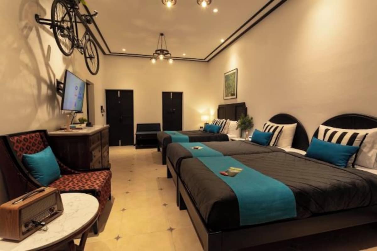 A modern bedroom with two beds, a desk, a chair, and a bicycle mounted on the wall.
