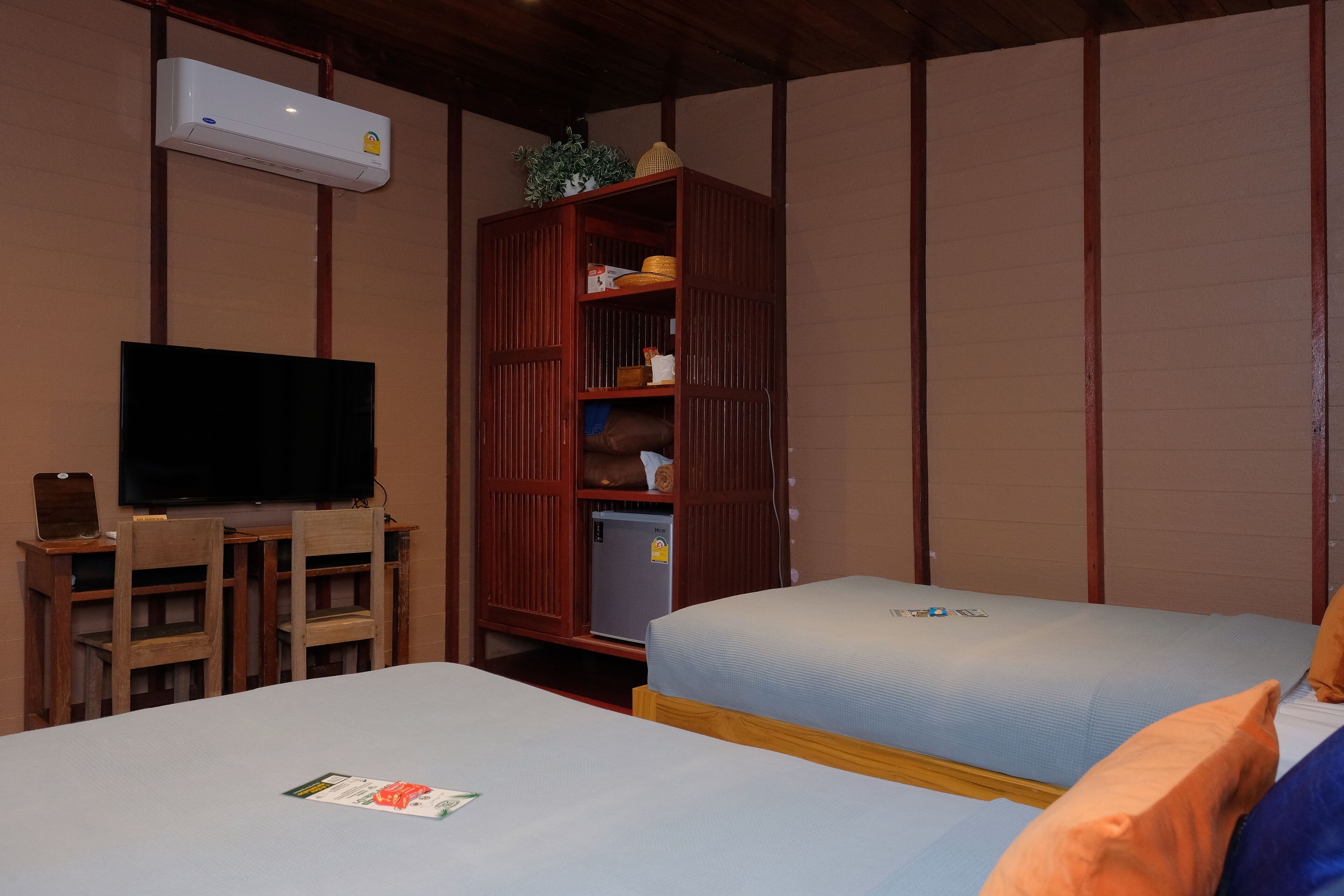 Una habitación con dos camas, televisión, escritorio de madera y armario.