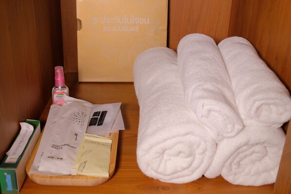 A wooden shelf with toiletries, a box, and folded towels. - Suan Pa Khao Lom Homestay (Krok Phra)