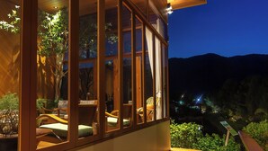 A modern building with large windows, wooden flooring, and a view of the mountains.