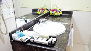 A bathroom with a marble countertop, a white sink, and a mirror above it. There are toiletries on the counter and a telephone on the wall. - Dancenter Top Star Heritage Village (Abu Dhabi)