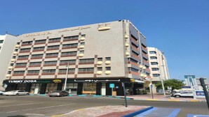 A hotel with multiple floors and balconies, a visible restaurant named "YUMMY DOSA" on the ground floor, and a clear blue sky in the background. - Dancenter Top Star Heritage Village (Abu Dhabi)