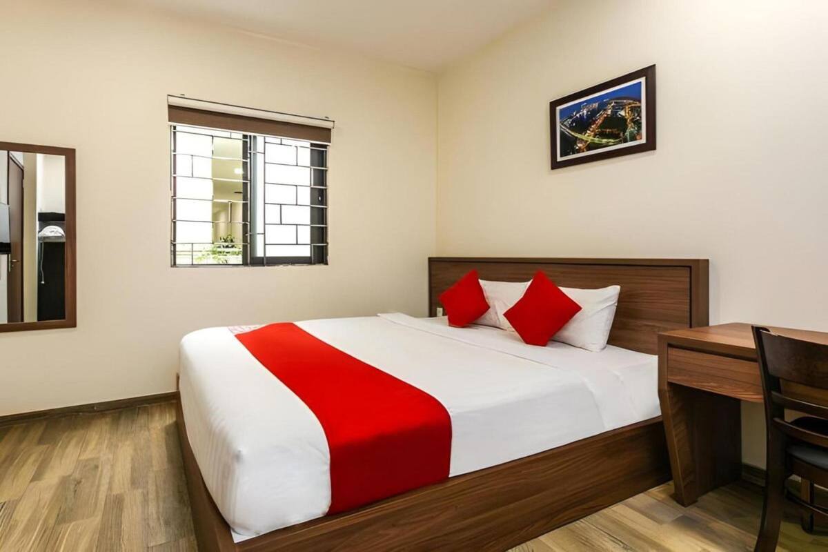 A hotel room with a wooden bed, a desk, and a window with metal bars.