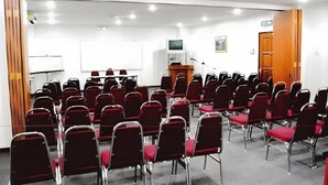 A conference room with rows of red chairs, a whiteboard, a podium, and a television on a stand. - Hotel O Ramai (Sandakan)