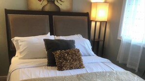 A neatly made bed with a patterned bedspread, a dark pillow, and a decorative pillow. - Turnagain inn  (Anchorage)