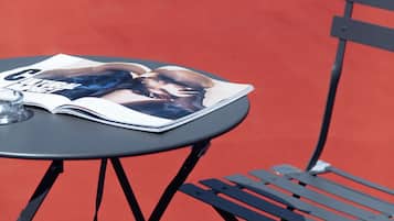 A table with a magazine on it and a metal chair beside it.