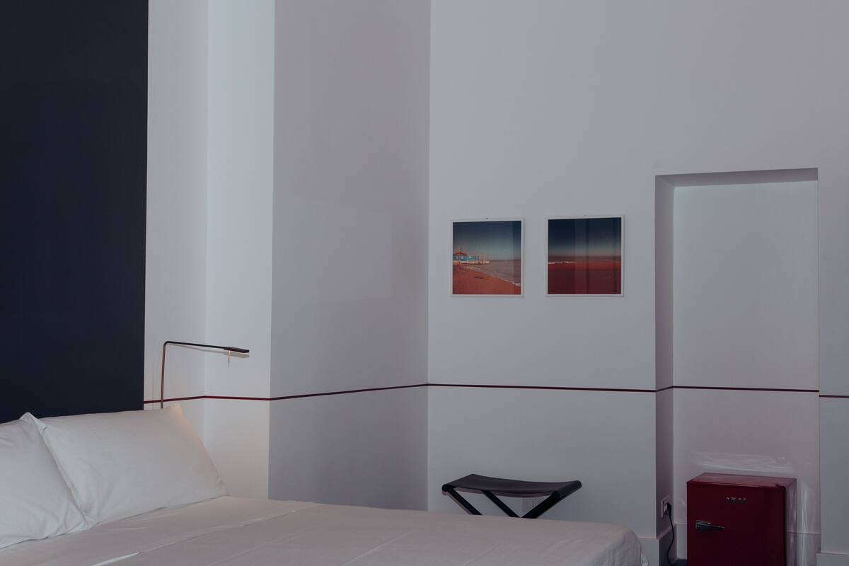 A hotel room with a bed, a desk, a chair, and a red safe.