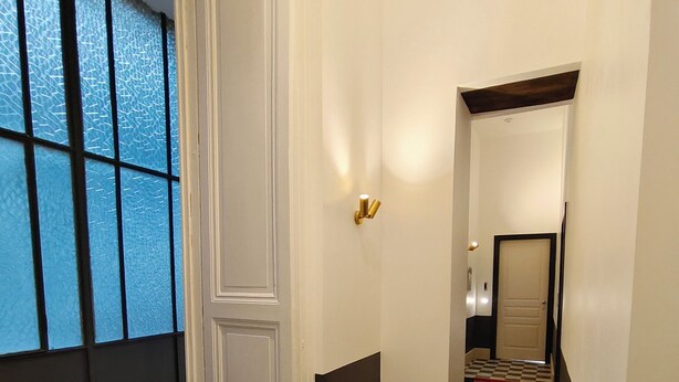 A hallway with a checkered floor, a white door, and a window with blue-tinted glass. - Altoledo Rooms and Suite (Naples)