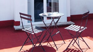 A white building with a glass door and a small table with two chairs. - Altoledo Rooms and Suite (Naples)