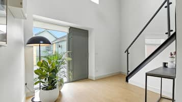 Un interior moderno con una escalera, una planta en maceta y vistas a través de una puerta.