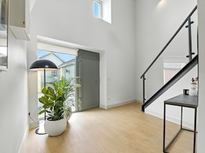 A modern interior with a staircase, a potted plant, and a view through a door. - The Warehouse Clifden (Clifden)