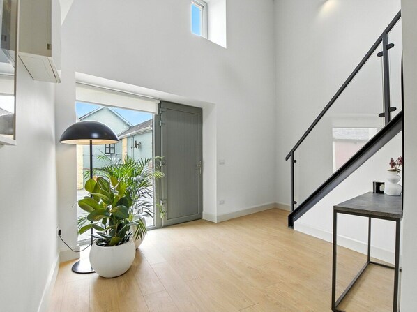 A modern interior with a staircase, a potted plant, and a view through a door.