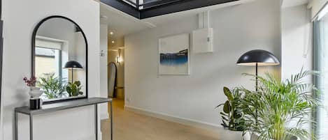 A modern interior with a console table, a large mirror, and potted plants.