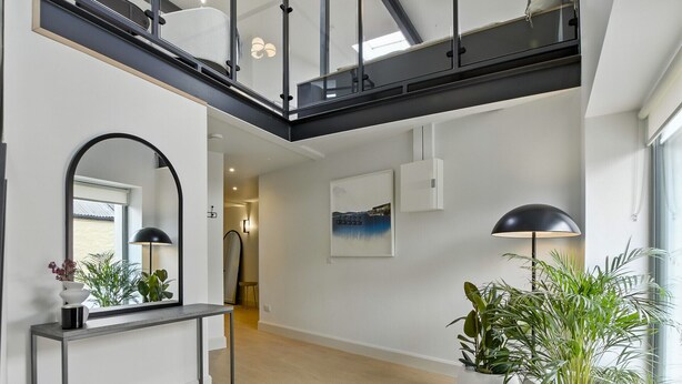 A spacious hallway with a high ceiling, a staircase, and a view of a cityscape through large windows. - The Warehouse, Clifden Modern and elegant (Clifden)
