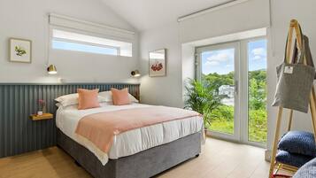 Un dormitorio con una cama, una ventana, una planta y un cuadro sobre caballetes.