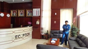 A reception area with a reception desk, framed portraits, a clock, and a seating area with a sofa and a coffee table. - OYO 1558 Belvilla Top Stars Hotel Near Gold Souk (Abu Dhabi)