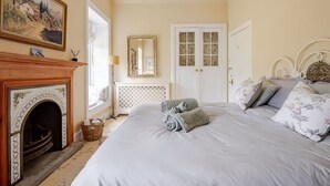 Un dormitorio con chimenea, una cama con toallas enrolladas, un espejo y una puerta con paneles de vidrio.