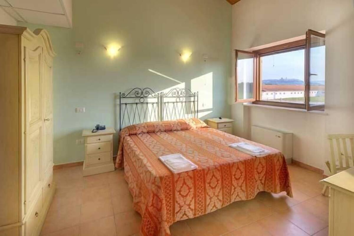 A bedroom with a bed, a nightstand, a dresser, a window with a view, and a ceiling fan.