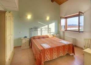 A bedroom with a bed, a nightstand, a dresser, a window with a view, and a ceiling fan.