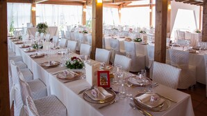 A long banquet table set for a formal event, with white tablecloths, neatly arranged chairs, and a floral centerpiece. - Miraconero (Porto Recanati)