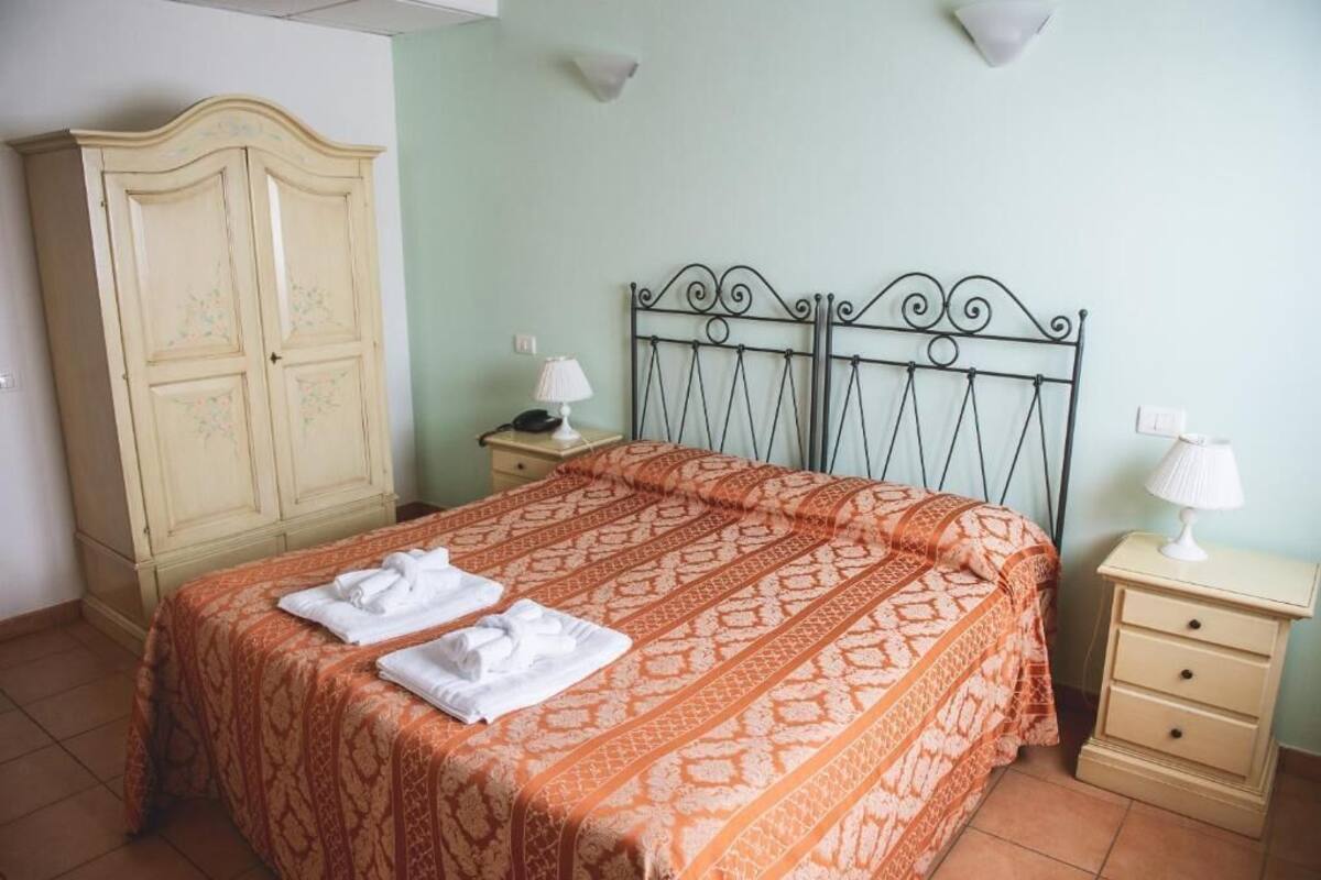 A bedroom with a bed, two bedside tables, a wardrobe, and wall-mounted lamps.