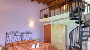 A bedroom with a bed, a wardrobe, a staircase, and a wall-mounted light fixture. - Miraconero (Porto Recanati)