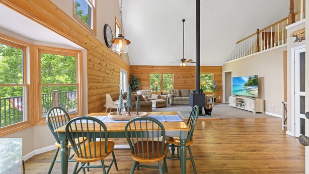 A spacious living area with a wooden floor, a dining table with chairs, a fireplace, and a television. - Timber Ridge Retreat by Chatuge Home Concierge | Serene Mountain Escape · Stunning Year-Round Views · Gated Community (Hiawassee)