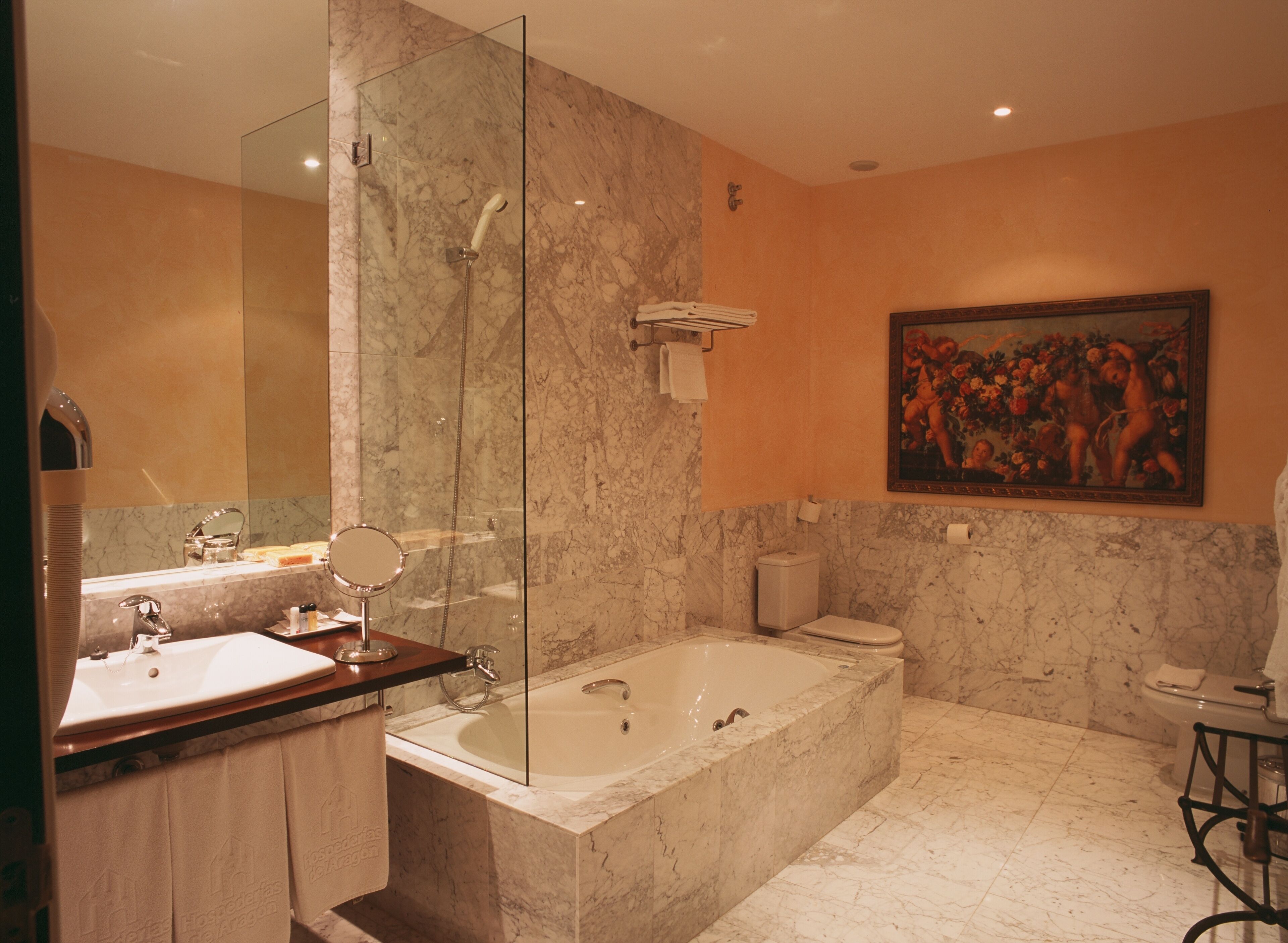 Ein modernes Badezimmer mit einer begehbaren Glasdusche, einer freistehenden Badewanne, einem Waschtisch mit Spiegel und einer Toilette.