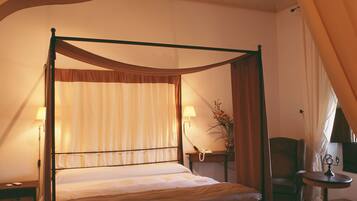 A four-poster bed with a canopy, a bedside table with a lamp, a chair, and a small table with a decorative item.